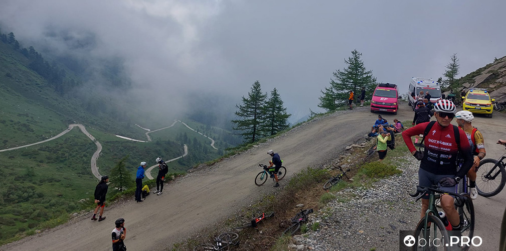 Quasi in vetta arriva la foschia, si accumulano tifosi in bici e mezzi dei team mentre si sta decidendo l'accorciamento della tappa